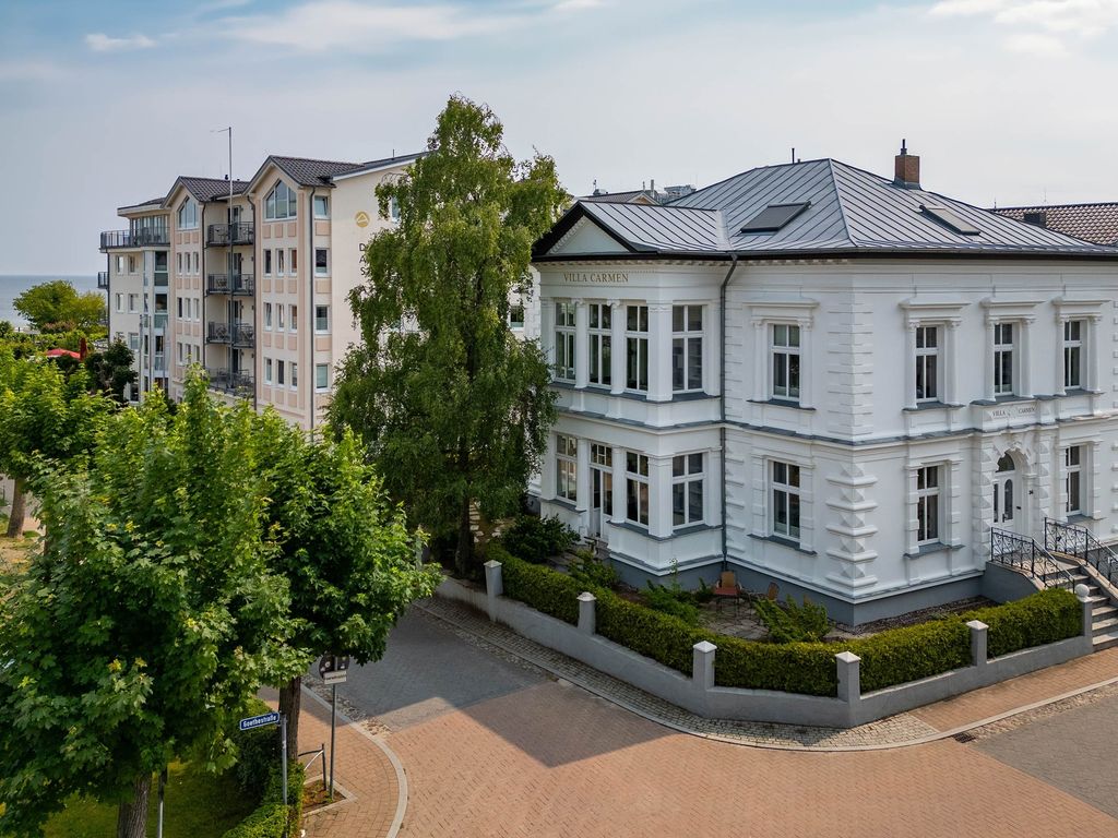 Villa Carmen Ahlbeck – weiße Bädervilla mit Schriftzug und Zinkdach, dahinter die Ostsee