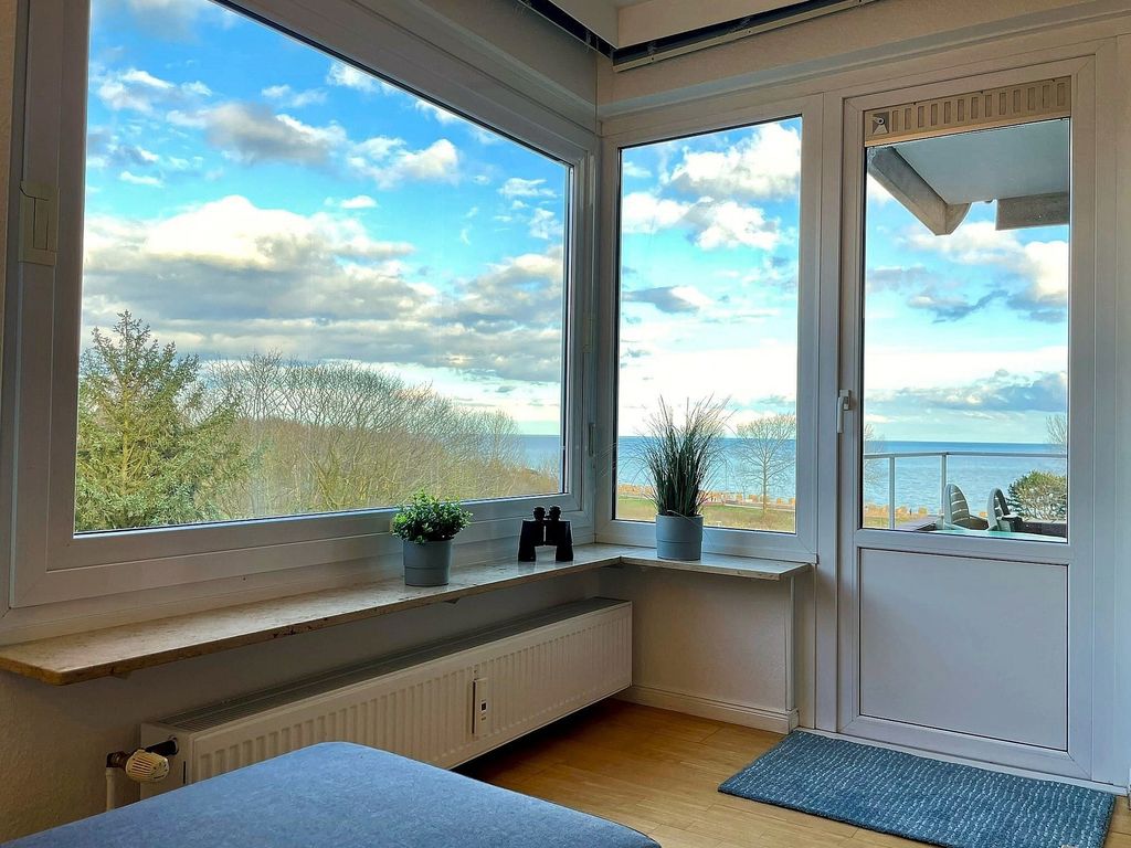 Hanseat Grömitz – weiter Blick vom Balkon über die Strandwiese auf die sonnenbeschienene Ostsee