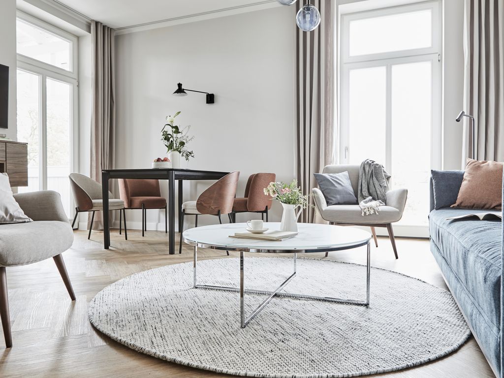 Villa Esperance Binz – Wohnraum einer Suite mit Samtsofa, Designsesseln und hohen Fenstern