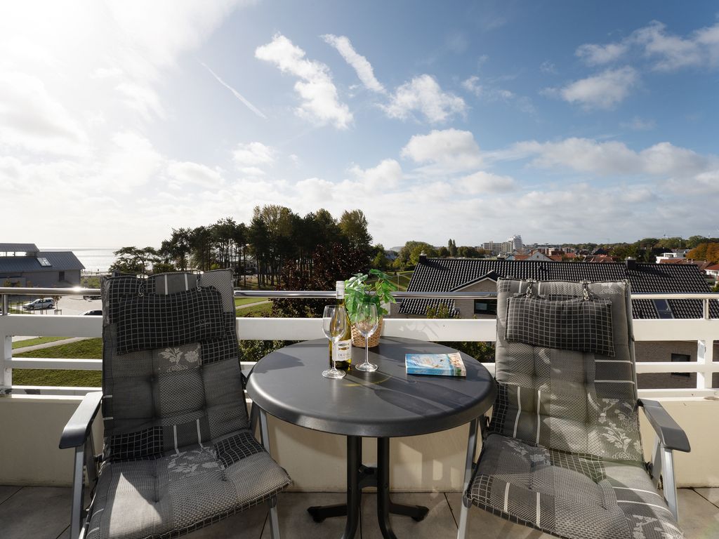 Belvedere Grömitz – Balkon mit Tisch und Stühlen und weitem Blick über Dächer und Grün Richtung Ostsee