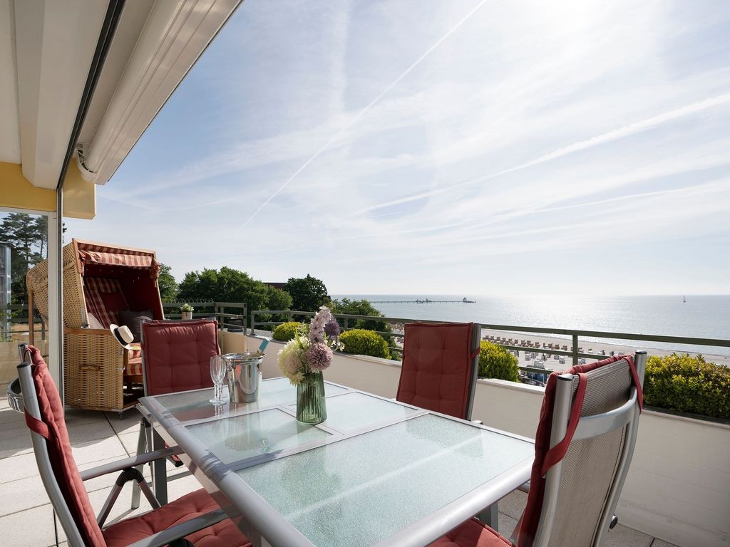 Miramar Grömitz – große Terrasse mit Strandkorb und weitem Blick über Promenade, Seebrücke und Ostsee