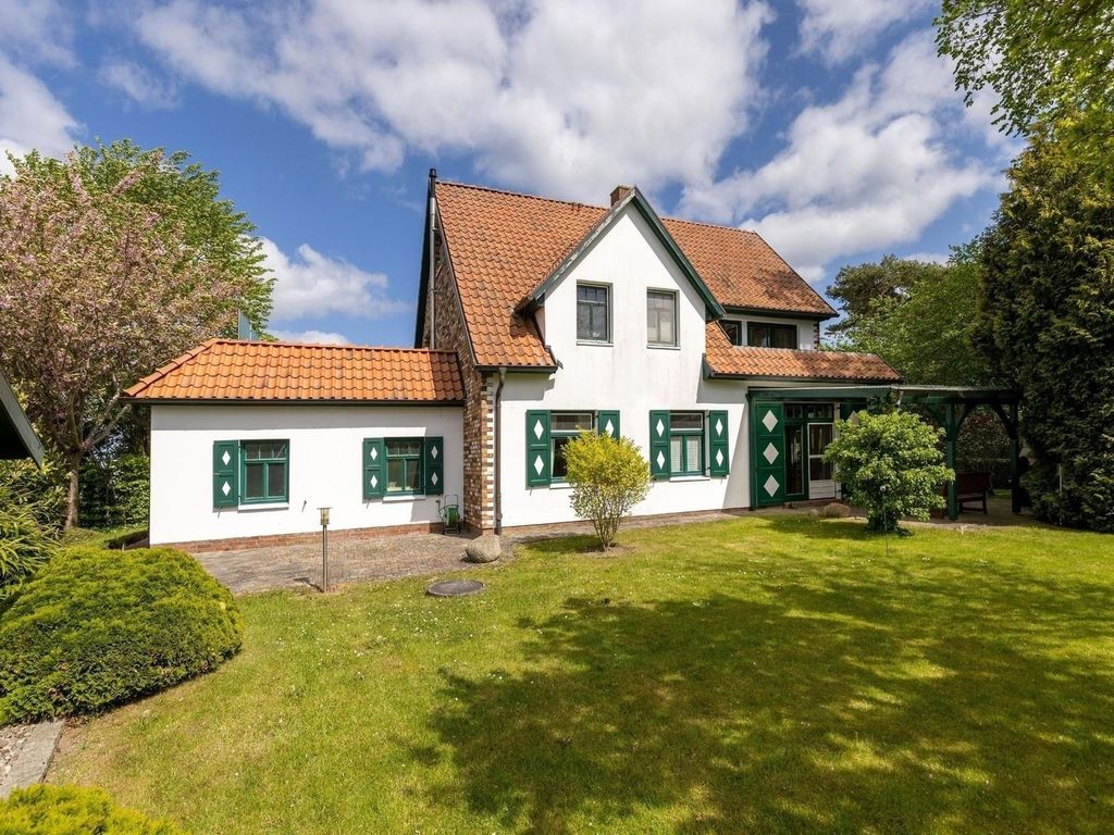 Ferienhaus Rügenbrise Garz – weißes Landhaus mit rotem Ziegeldach und grünen Fensterläden im Gartengrundstück