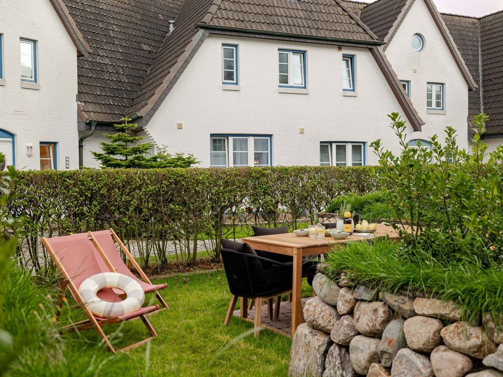 Kajüte Westerland – weiße Reetdachhäuser der Anlage mit Gartenterrasse und Liegestuhl