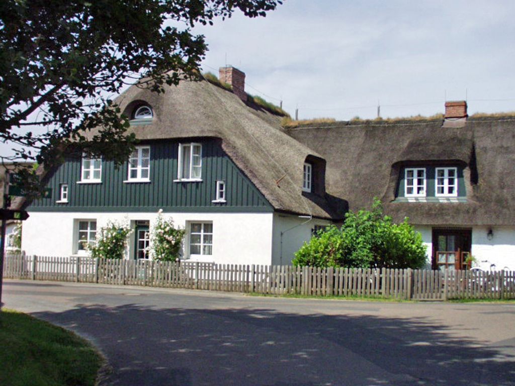 Landhaus am Meer Utersum – reetgedecktes Friesenhaus mit grüner Holzfassade und weißem Staketenzaun