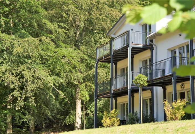 Haus Waldidyll Sellin – weißer Neubau mit umlaufenden Stahlbalkonen direkt am Waldrand
