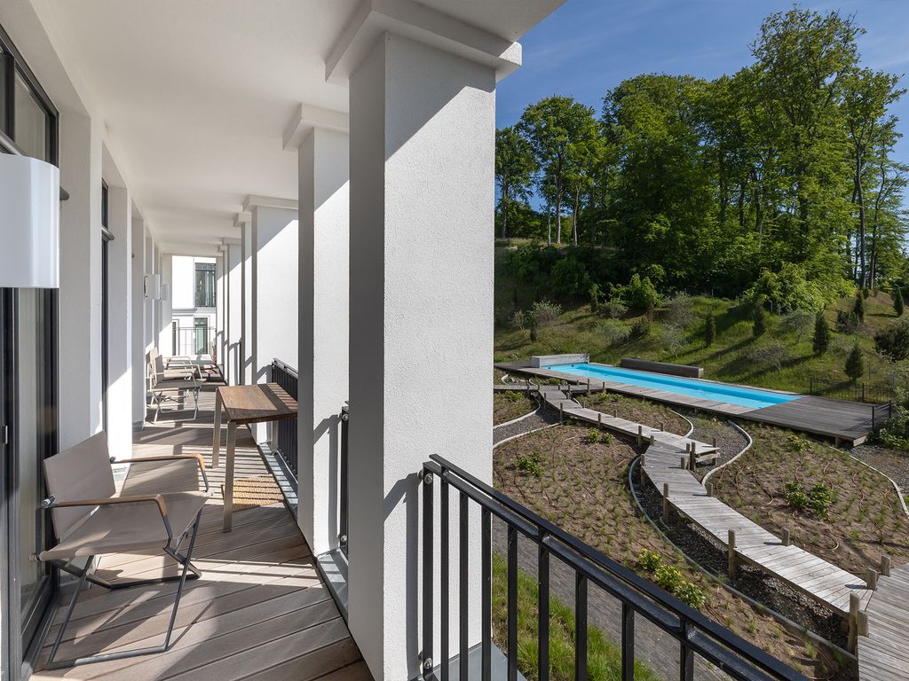 Villa Claire Sellin – Balkon mit Blick auf den Außenpool und den bewaldeten Hang