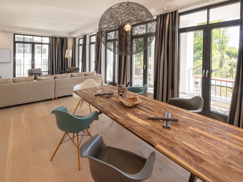 Villa Claire Sellin – langer Massivholztisch mit Designstühlen vor der Balkontür
