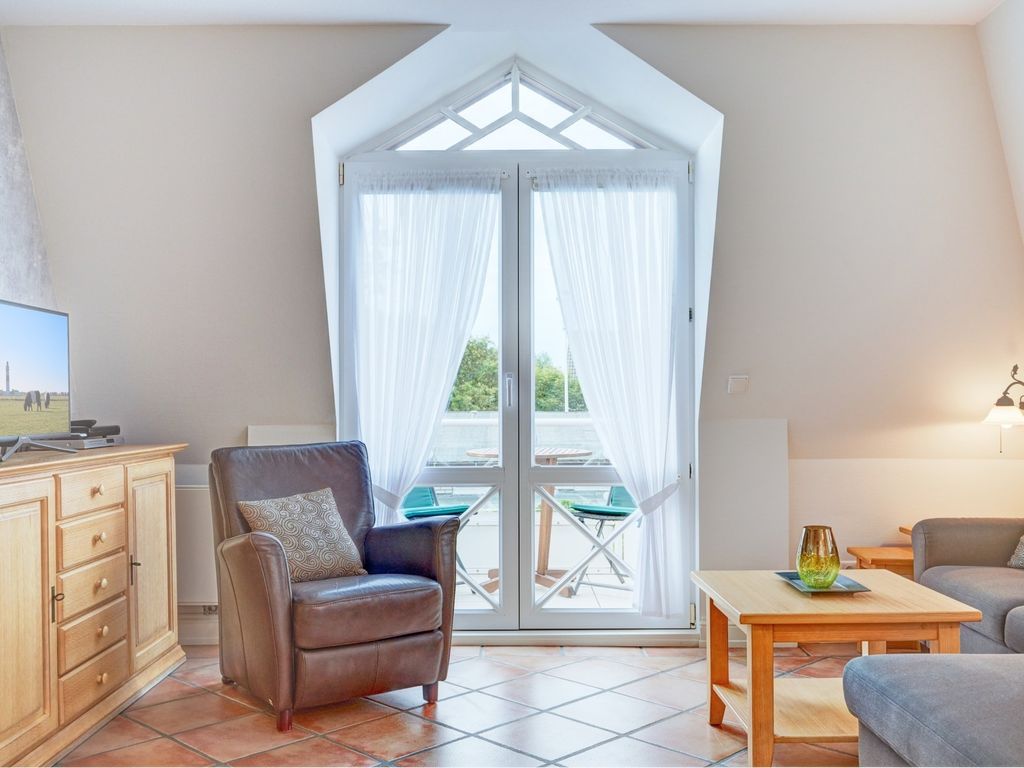 Zur Alten Gärtnerei Westerland – gemütlicher Wohnraum mit Ecksofa und Strandmotiven