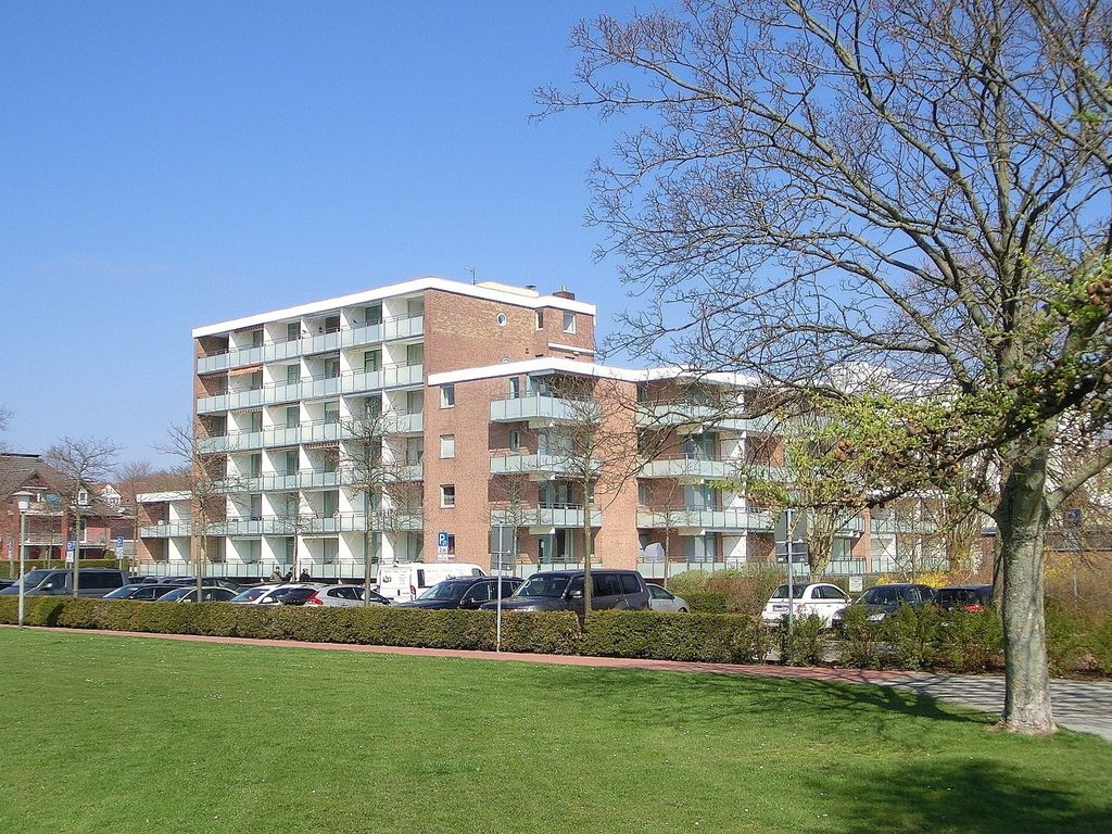 Fürstenhof Grömitz – mehrgeschossiges Apartmenthaus aus rotem Klinker mit umlaufenden Balkonen, davor Rasenfläche und Bäume