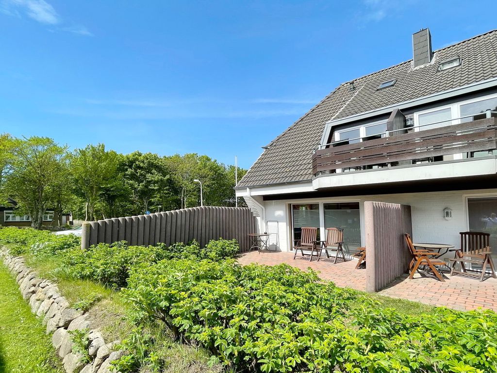 Ruusenhüs Westerland – Ferienhaus mit Satteldach, Balkonen und Terrasse hinter grüner Hecke