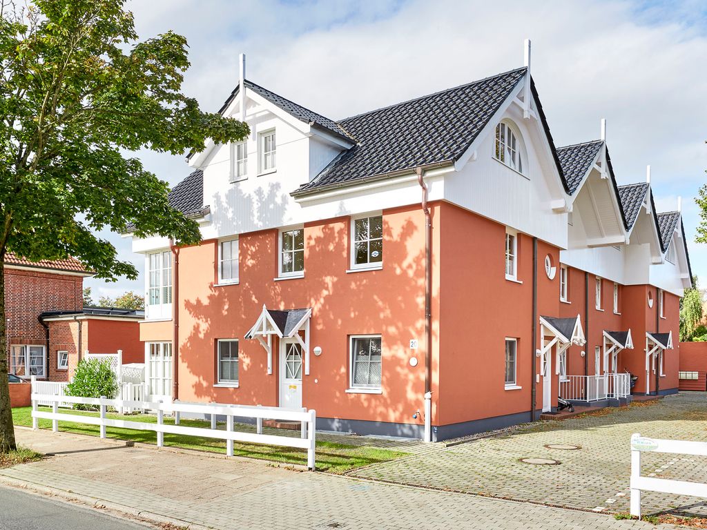 Haus an der Altstadt Wyk – lachsfarbenes Reihenhaus-Ensemble mit weißen Giebeln und Vorgarten an der Straße