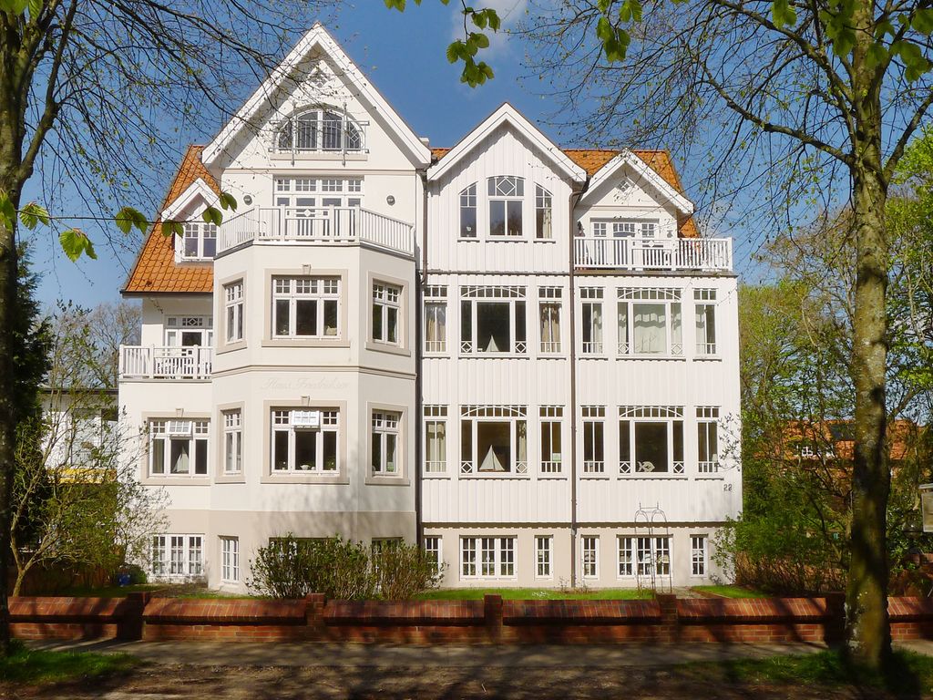 Haus Friedrichsen Wyk – weiße Holzvilla mit Giebeln, Erkern und Balkonen hinter Buchen