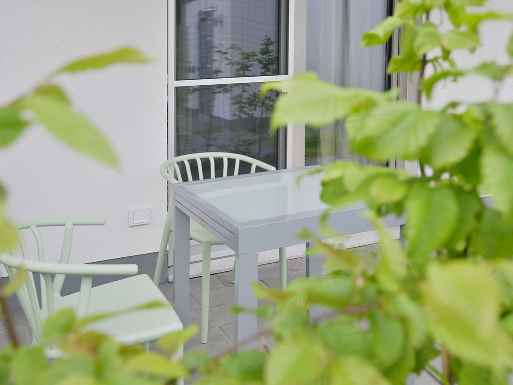 KOSI am Meer Koserow – Terrasse mit Tisch und Stühlen an der hellen Hausfassade