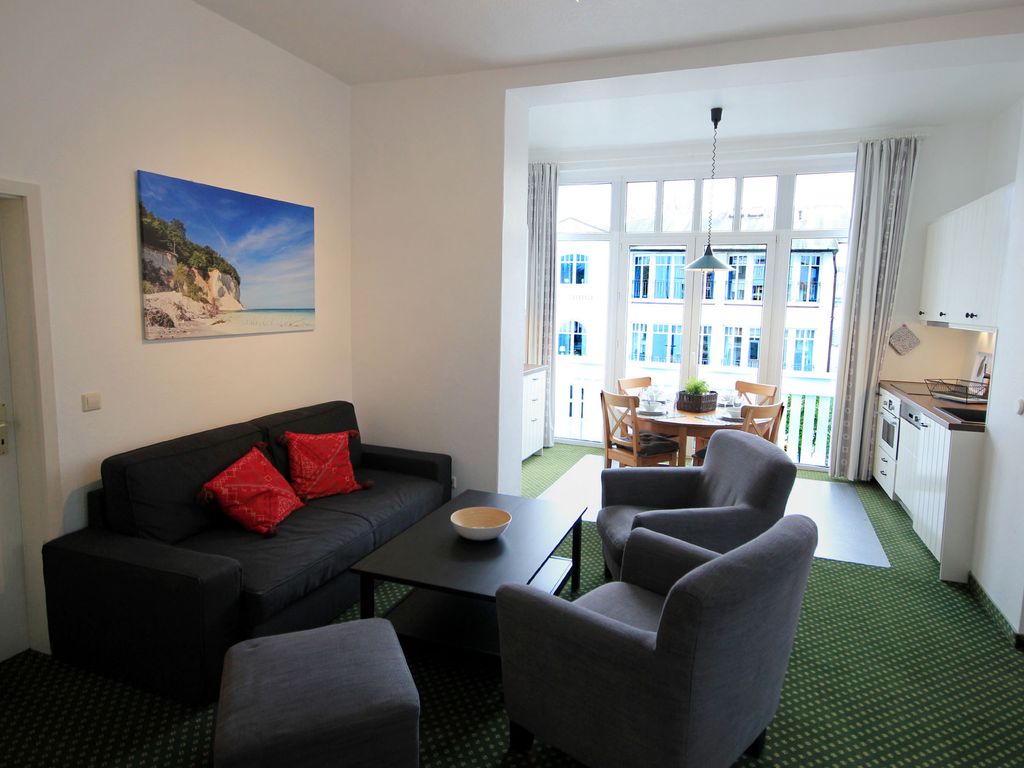 Haus Felicitas Binz – Wohnraum mit Sofa, Sesseln und Essplatz im Erker vor dem Balkonfenster