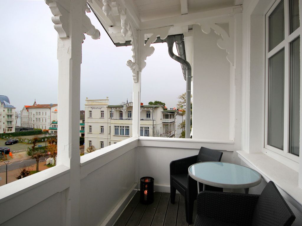 Haus Felicitas Binz – geschnitzter Loggia-Balkon mit Bistrotisch und Blick auf die Villen der Straße