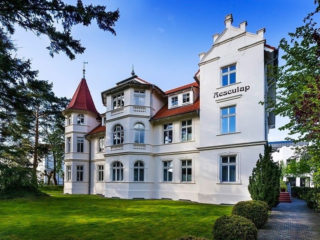 Villa Aesculap Binz – weiße Bädervilla mit Turm und rotem Dach im Grünen