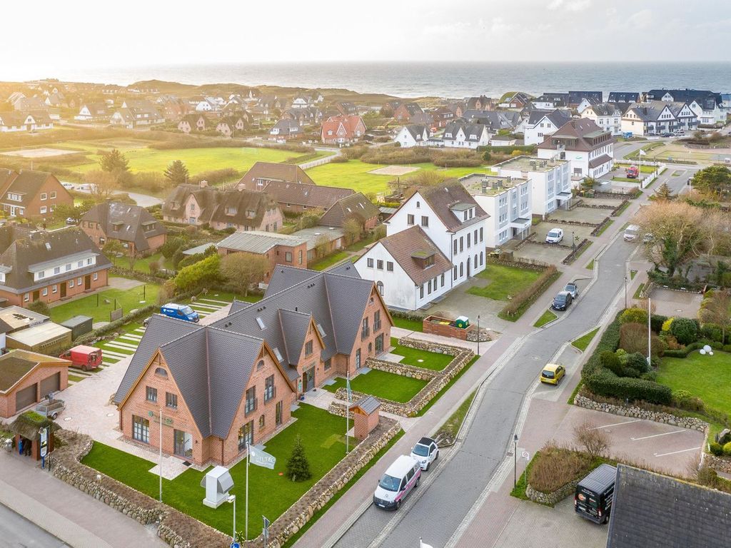 Strandgut in Wenningstedt auf Sylt: Luftaufnahme der Backsteinhäuser mit Blick über den Ort zur Nordsee