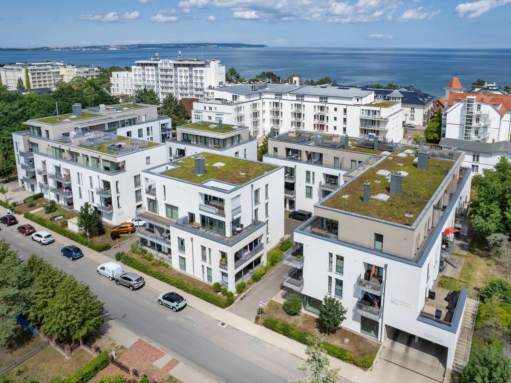 DünenResort Binz – Luftbild der weißen Neubau-Häuser mit begrünten Dächern, dahinter die Ostsee