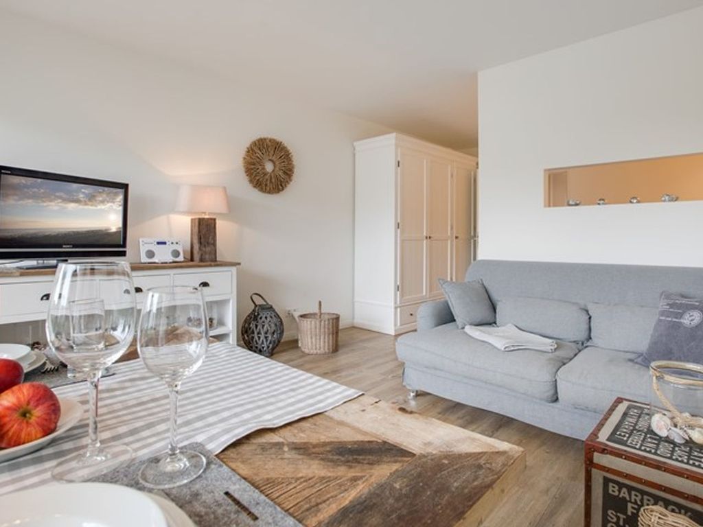 Haus Weststrand Westerland – maritimer Wohnraum mit gekalktem Dielenboden und Rattansessel