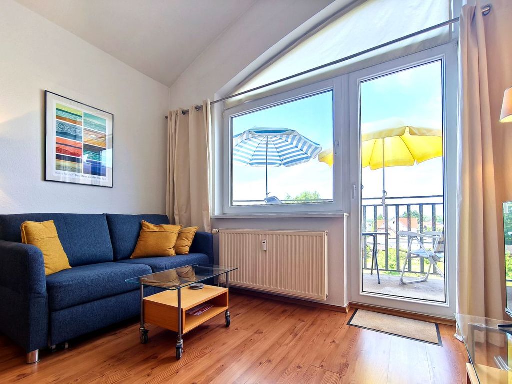 Lichtdurchfluteter Wohnbereich mit blauer Couch und Zugang zum Balkon