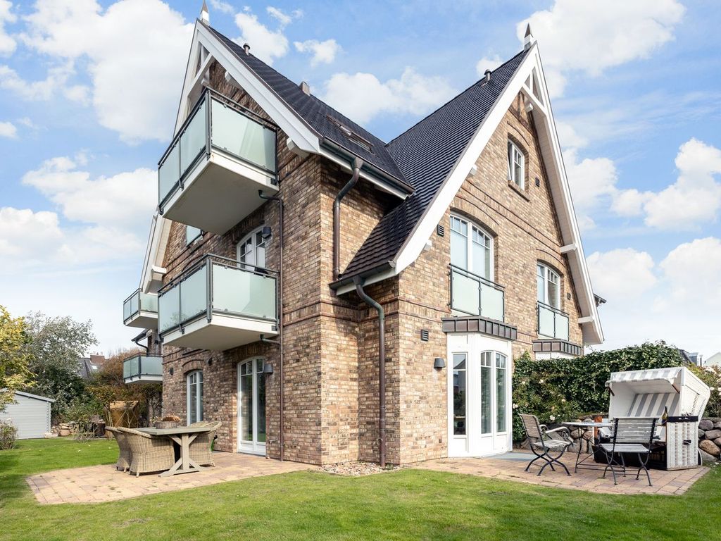 Landhaus Berthin-Bleeg in Wenningstedt auf Sylt: Außenansicht des Backsteinhauses mit Balkonen, Garten und Strandkorb