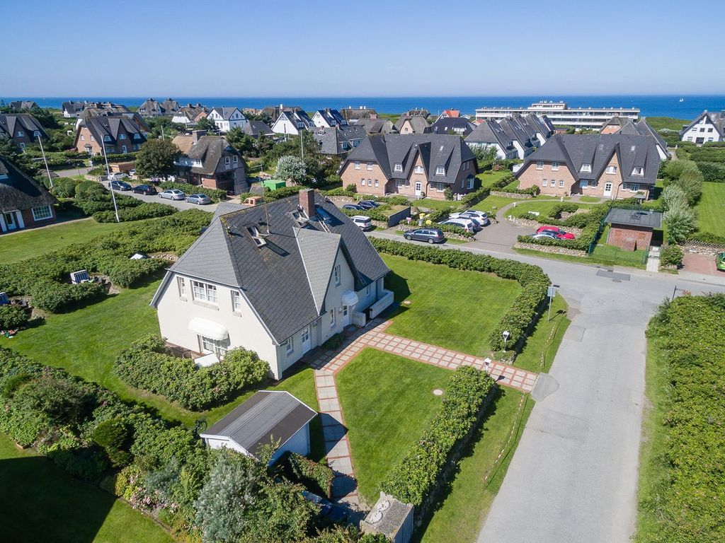Haus Heideresidenz in Wenningstedt auf Sylt – Luftaufnahme des Hauses mit Garten inmitten der Reetdachsiedlung, im Hintergrund die Ostsee