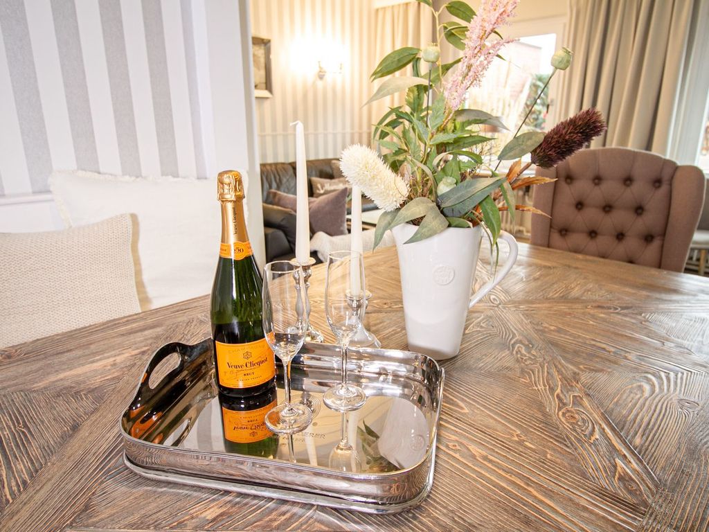 Nautic Lounge – Beach View: Champagner & Gläser auf stilvollem Esstisch mit Blumendeko.