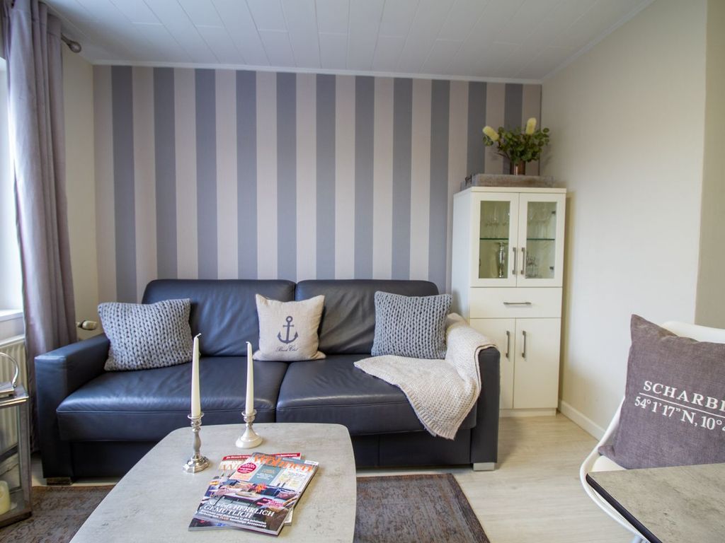 Stilvoller Wohnbereich der Nautic Lounge – Beach House 1 mit gemütlichem Sofa, maritimer Deko und eleganter Vitrine.