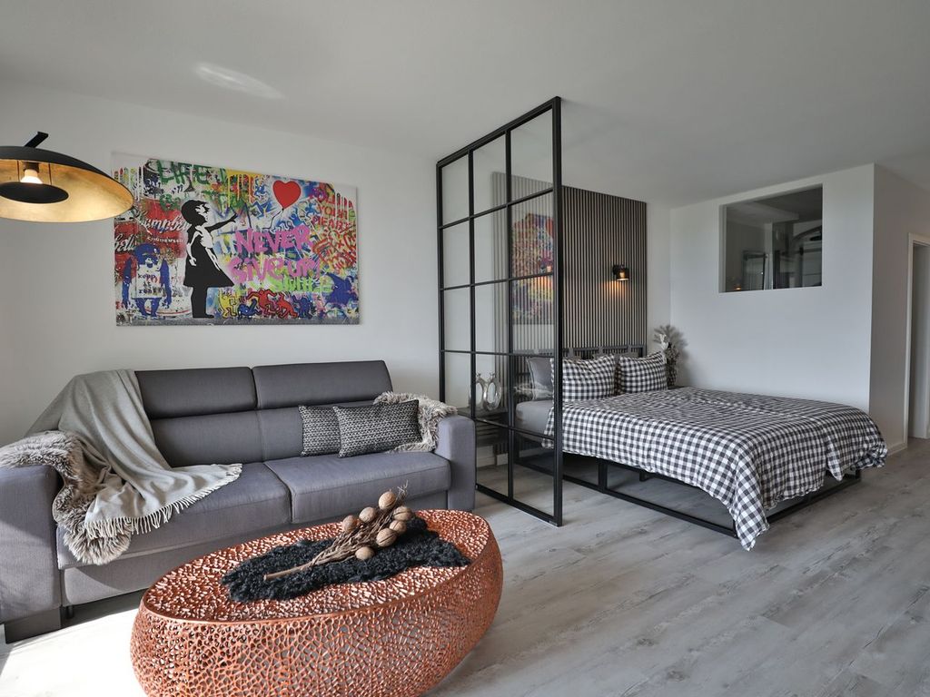 Strandkoje 7: Stylischer Wohn- und Schlafbereich mit Sofa, Boxspringbett und Raumtrenner.