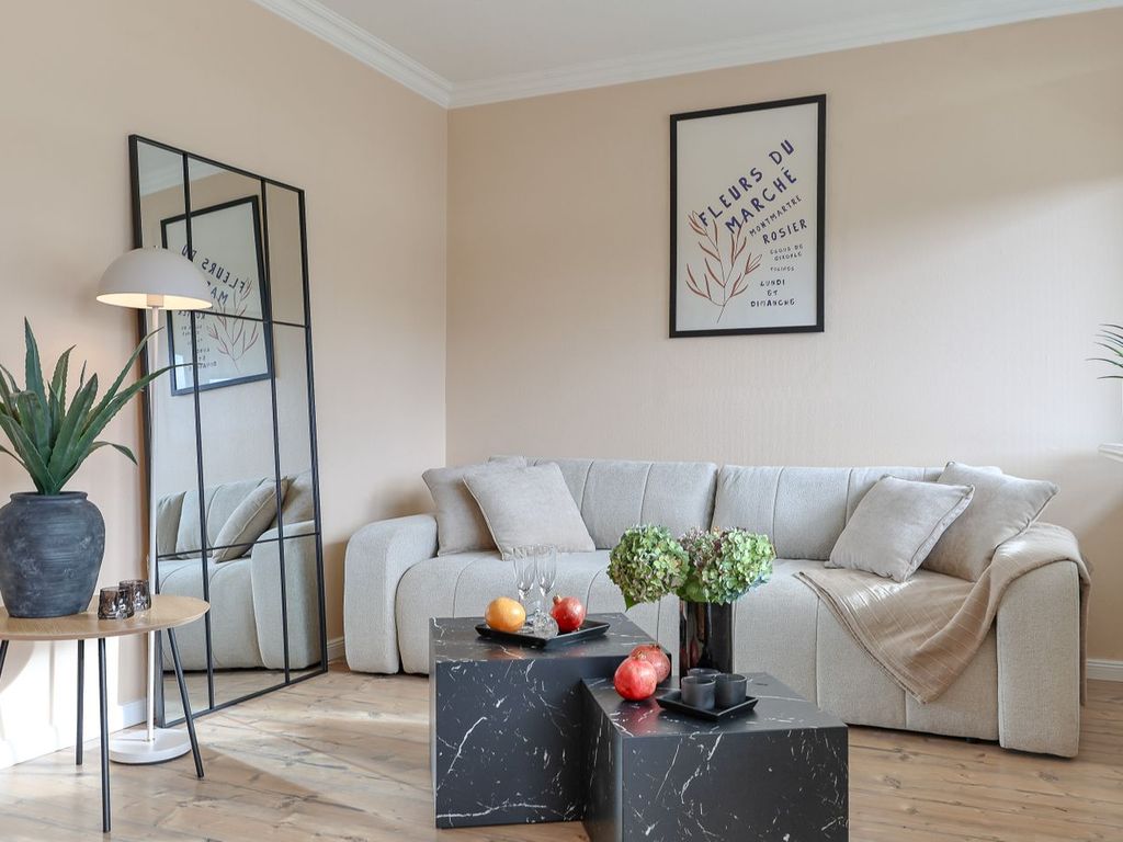 Haus Weststrand Westerland – heller Wohnbereich mit Bouclé-Ecksofa und bodentiefen Fenstern