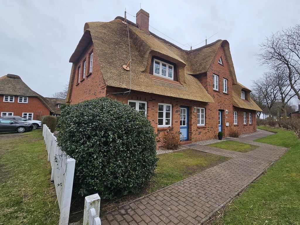 Außenansicht eines Hauses mit Reetdach und ruhigem Garten.
