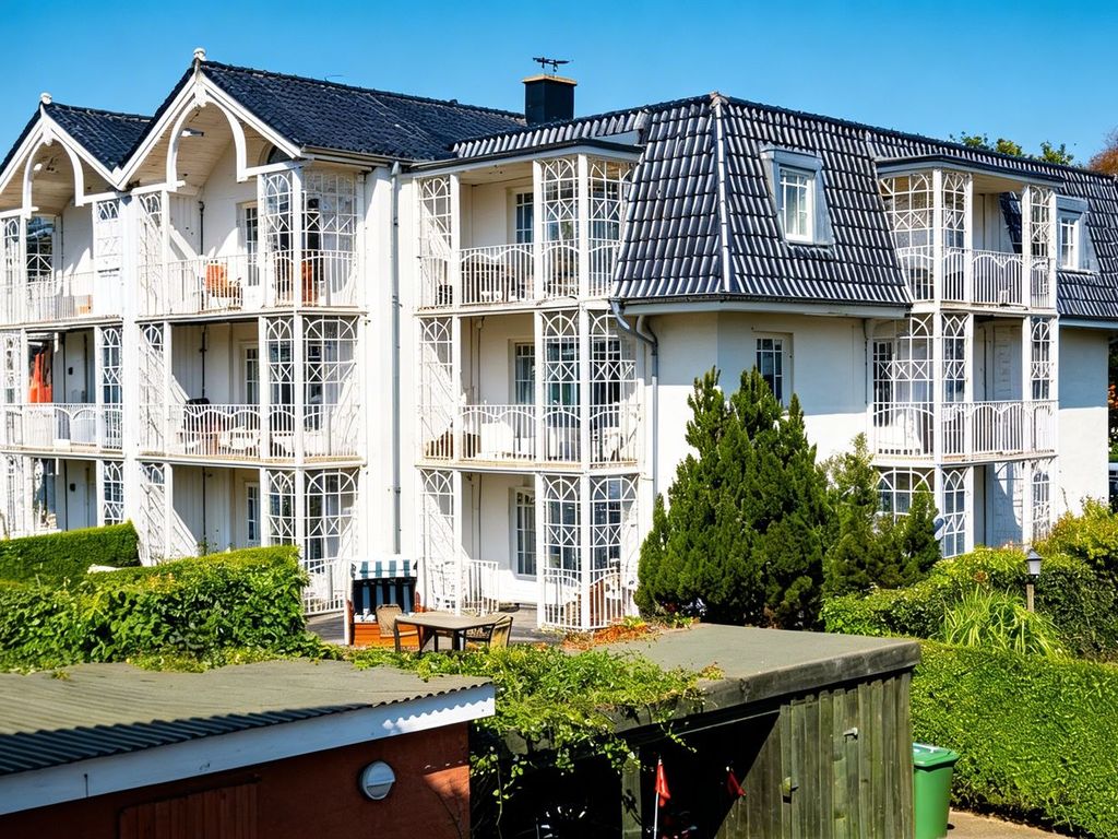 Palais am Südstrand Wyk – weißes Apartmenthaus mit verglasten Balkonen und dunklem Walmdach