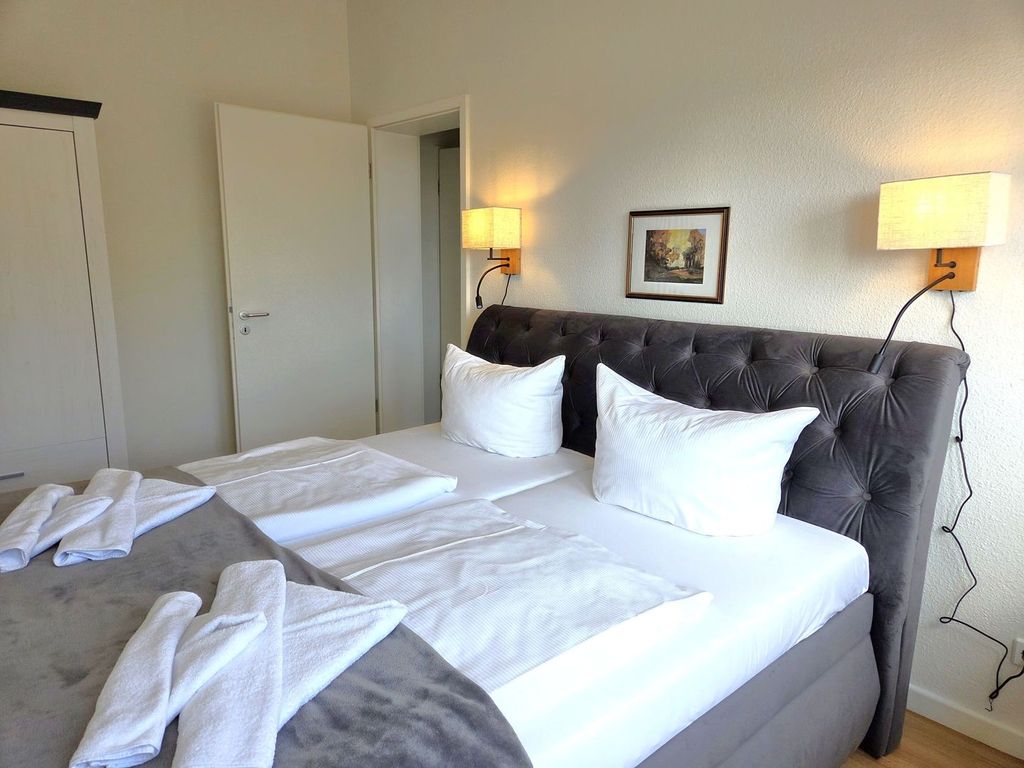 Alter Reichshof Sassnitz – Schlafbereich mit gepolstertem Bett und heller Möblierung