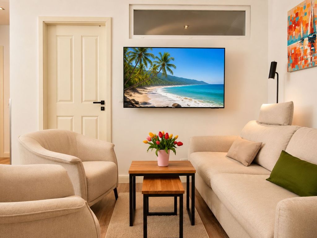 Wohnzimmer mit Sofa, Sesseln und TV