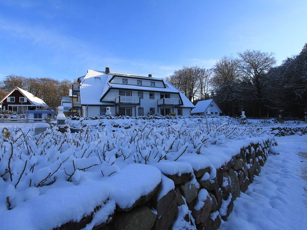 Romantische Winterimpression des tief verschneiten Ferienhauses unter blauem Himmel