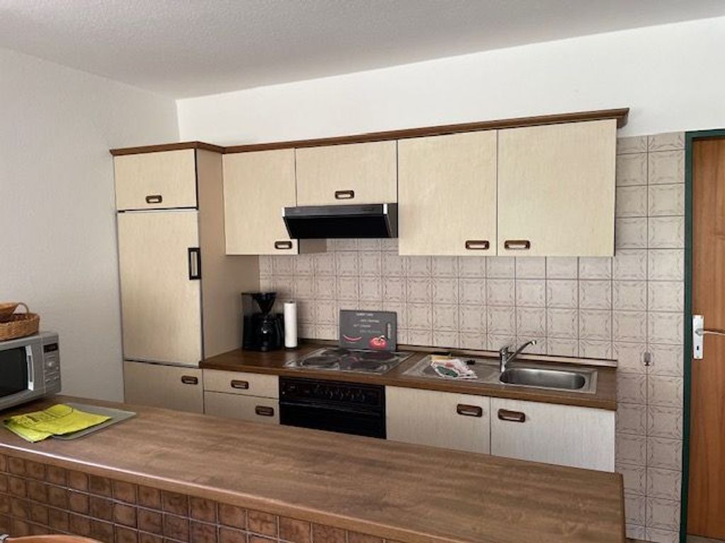 Küche mit Kühlschrank, Herd, Backofen und Spüle
