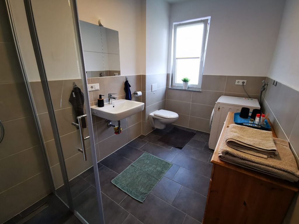 Badezimmer mit begehbarer Dusche und Waschmaschine, Handtücher werden gestellt