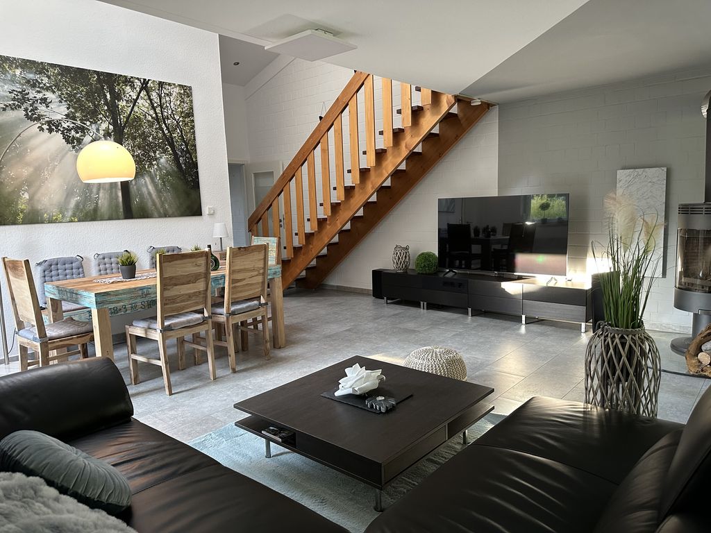 Blick ins Wohnzimmer mit Kamin, großem Smart TV - Fernsehr