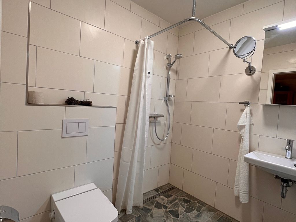Helles Badezimmer mit Natursteinboden und ebenerdiger Dusche