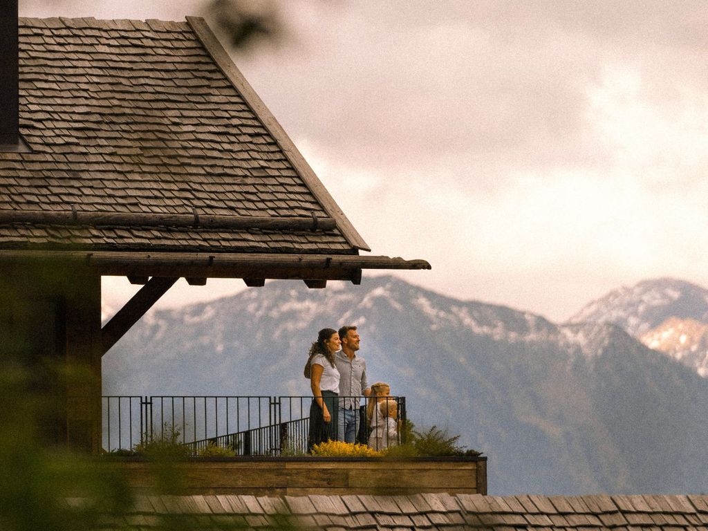 Familie auf dem Balkon eines Luxuschalets im neuen 5-Sterne-Family-Retreat in Ratschings mit Panoramablick auf die Südtiroler Alpen.