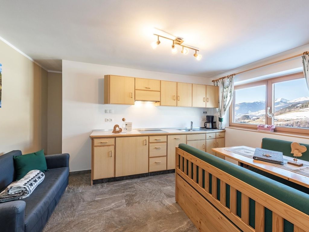 Wohnküche mit Panoramablick, komplett eingerichteter Küchenzeile in Massivholz und gemütlicher Couch.