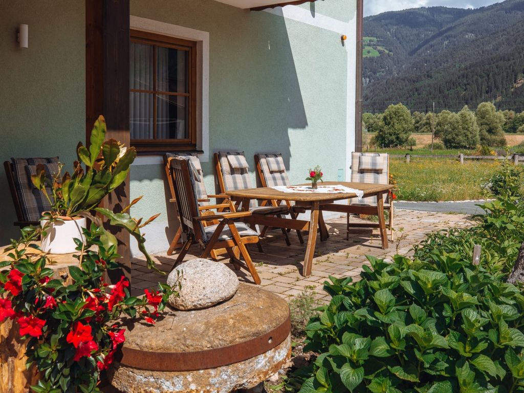 Die Terrasse des Bauernhofs mit einer Holzsitzgruppe und Bergblick.