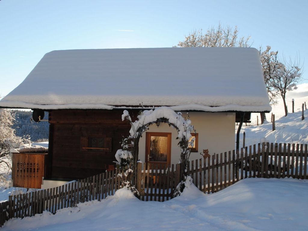 Das schneebedeckte Ferienhaus mit Holzzaun und Torbogen.