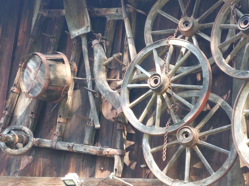 Traditionelle Dekoration der Almfassade mit historischen Wagenrädern und bäuerlichen Holzgeräten.