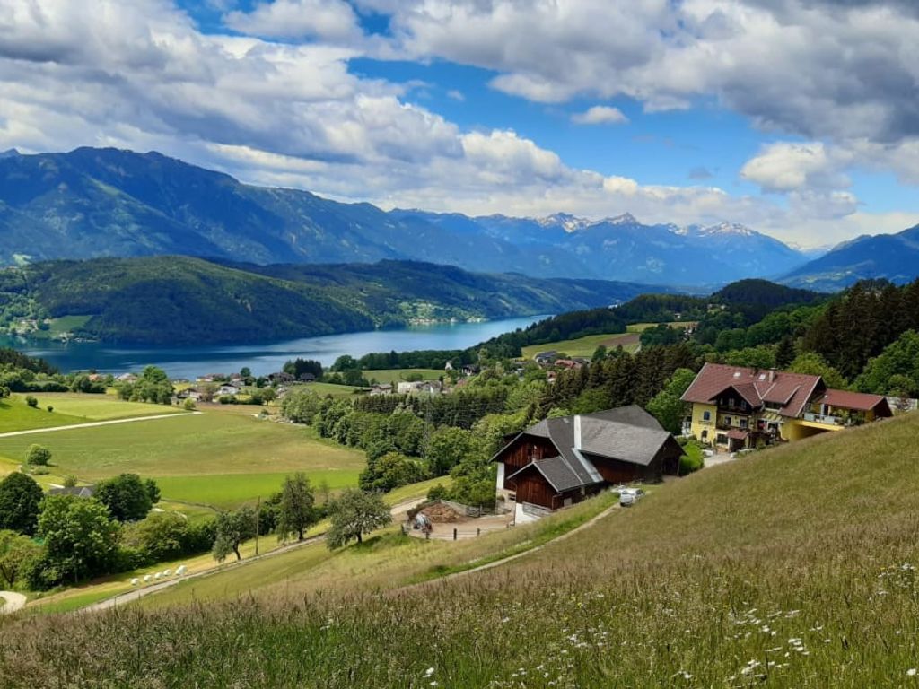 Der einladende Bauernhof, eingebettet in grüne Wiesen mit einem herrlichen Ausblick auf den schimmernden Millstätter See und die umliegende Berglandschaft.