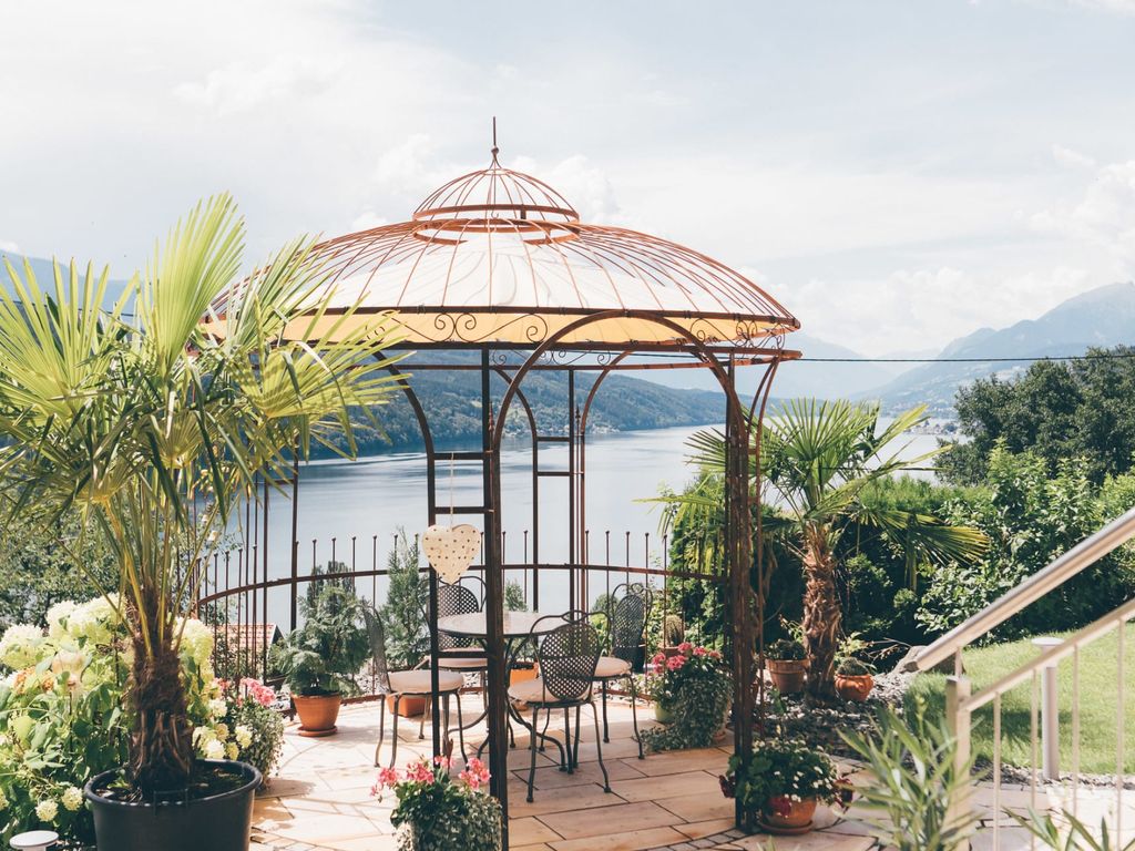Der Pavillon auf dem Bauernhof mit Tisch und Stühlen und Aussicht auf den See und die Berge.