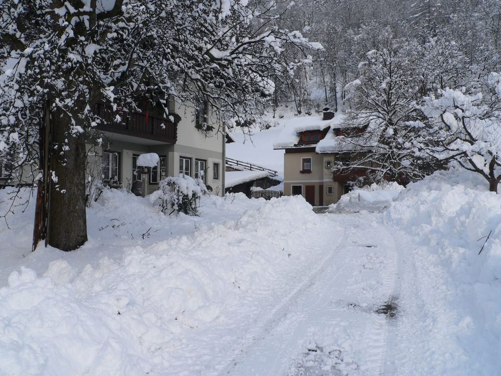 Außenansicht des Bauernhauses im Winter, umgeben von Schnee mit einem geräumten Zugangsweg.