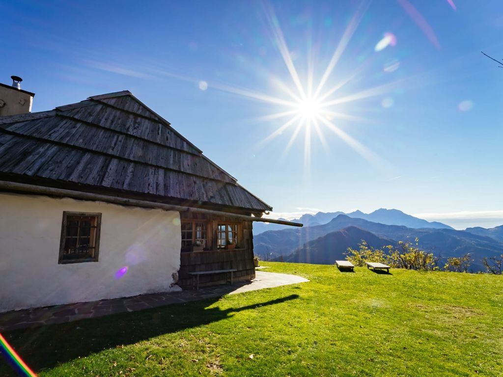 Der Hof mit grünem Rasen, Holzbänken und Blick auf die Berge.