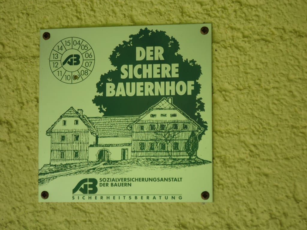 Das Schild an der Alm weist auf die Zertifizierung als Der sichere Bauernhof durch die Sozialversicherungsanstalt der Bauern hin.