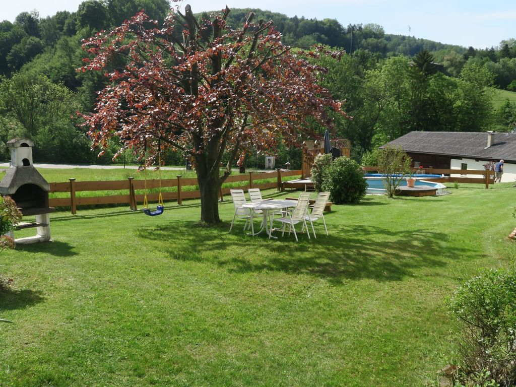 Der Gartenbereich des Bauernhofs umfasst eine Rasenfläche mit Pool, Grill, Schaukel und Sitzgelegenheiten unter einem Baum.